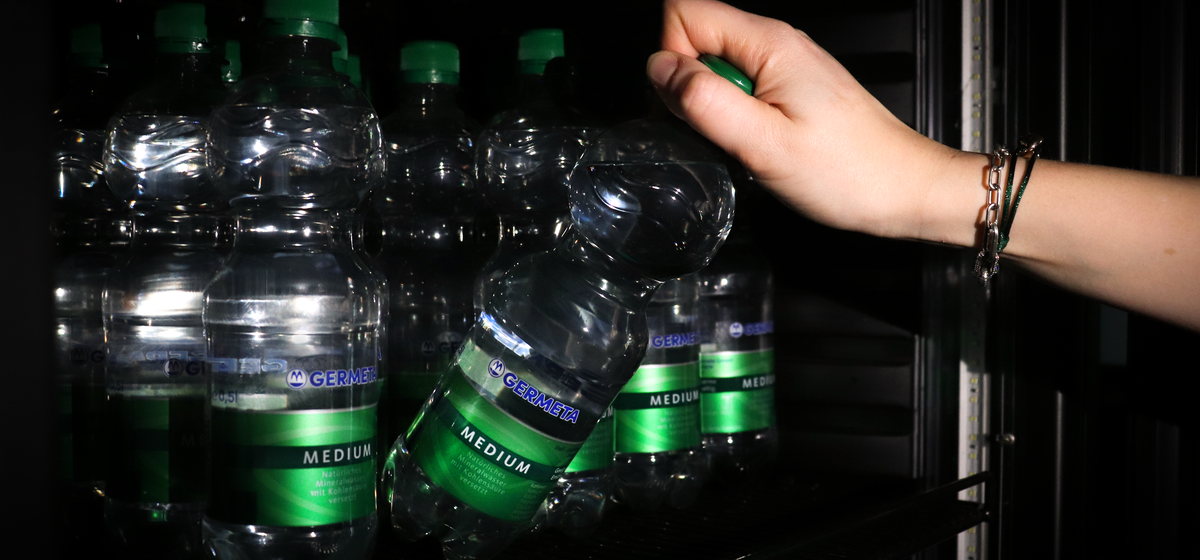Eine Hand greift in den Kühlschrank und nimmt sich eine Germeta Mineralwasserflasche Medium heraus.