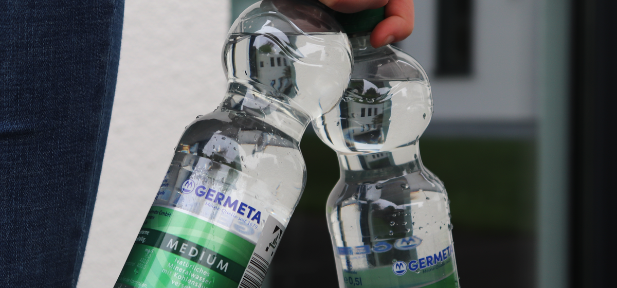 Hand hält zwei Germeta Mineralwasserflaschen Medium in der Hand. 