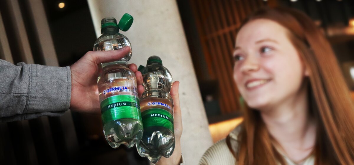 Zwei Personen stoßen mit einer Germeta Mineralwasserflasche Medium an.