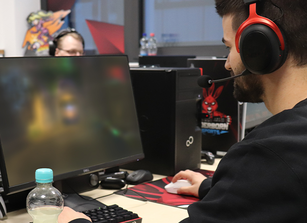 Ein Gamer sitzt an seinem PC neben anderen Spielern.